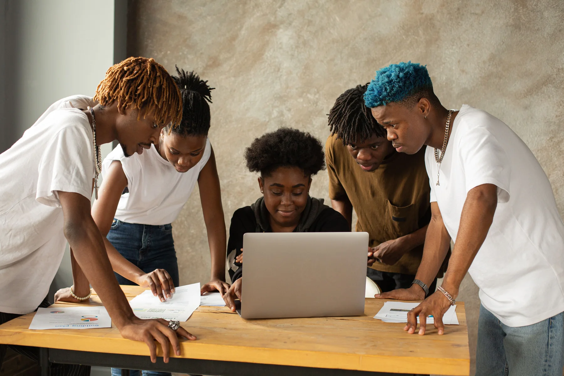 A diverse young team collaborating around a laptop during a project session
