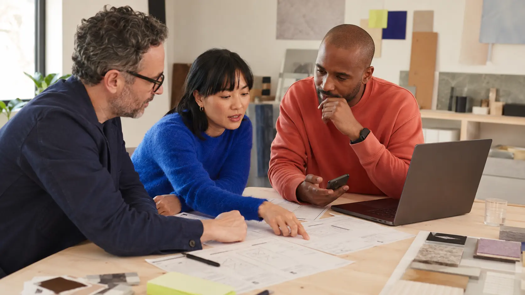 A product designer and software engineers reviewing wireframes and a mobile prototype