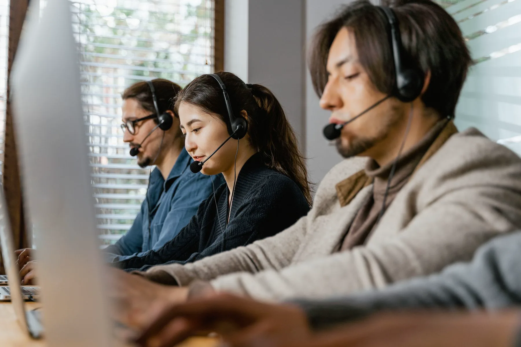 A customer operations team working with headsets and computers